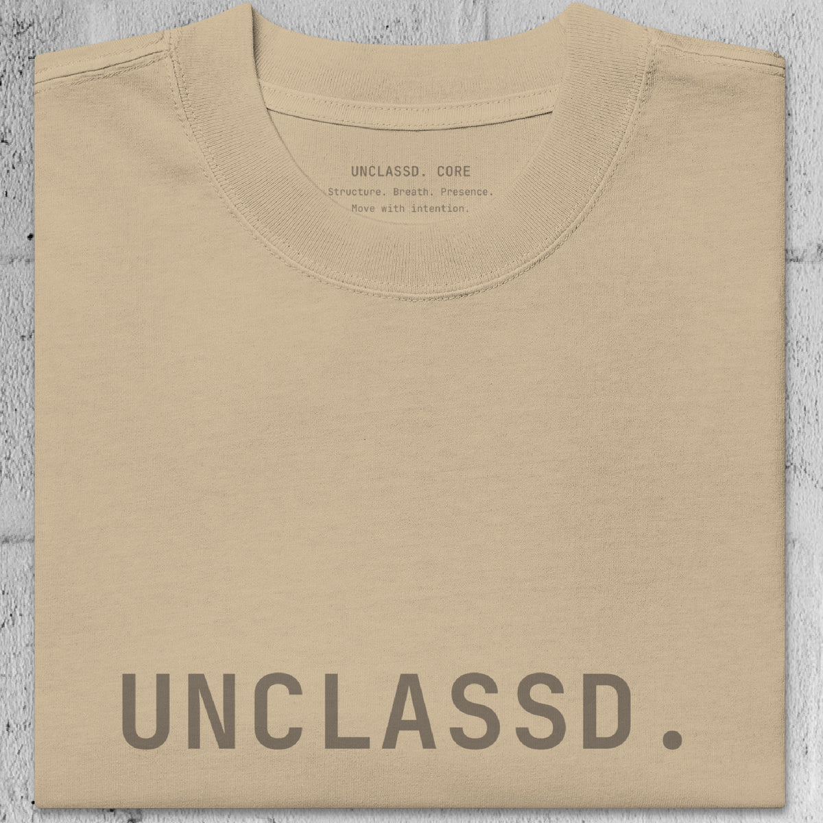 Close-up of faded khaki/beige heavyweight 240gsm cotton texture from the UNCLASSD CORE Oversized Tee, garment-dyed surface.
